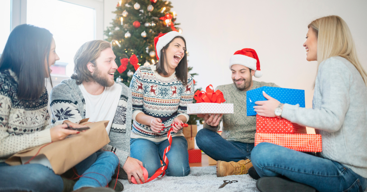 Friends laughing and enjoying a Secret Santa gift exchange